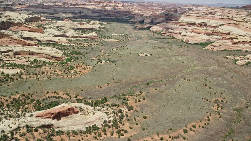 an aerial shot of a box canyon in Canyonlands National Park Utah showcasing the stunning green valley and unique rock formations captured during a sunny day in the arid wilderness