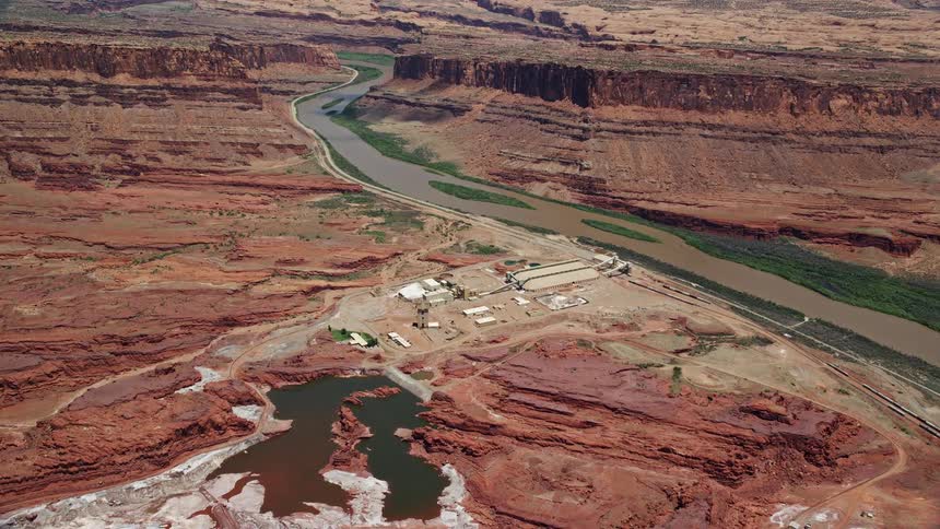 Approaching Intrepid Potash plant by Colorado River in Moab Utah with a sunny day time view of the arid and industrial surroundings