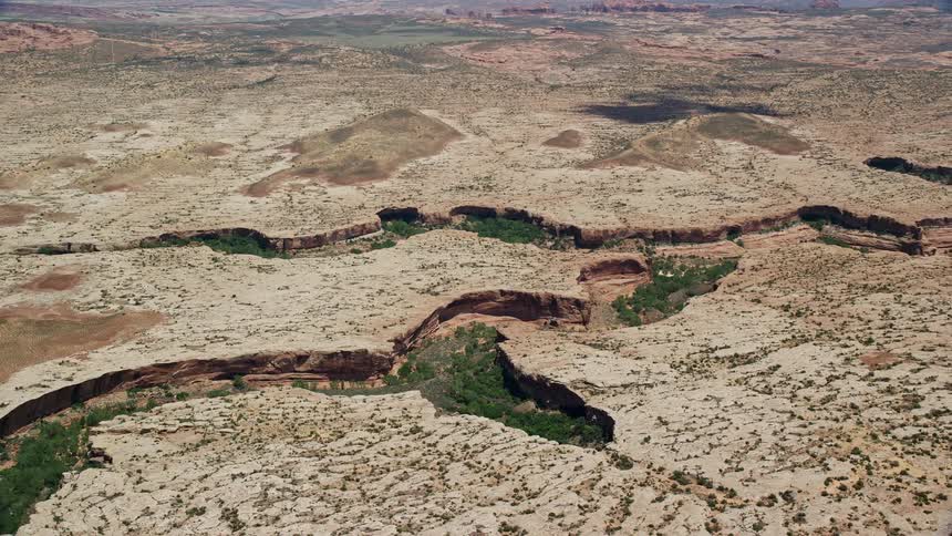  aerial footage showcases stunning desert canyons in Moab Utah with green vegetation amidst the arid landscape