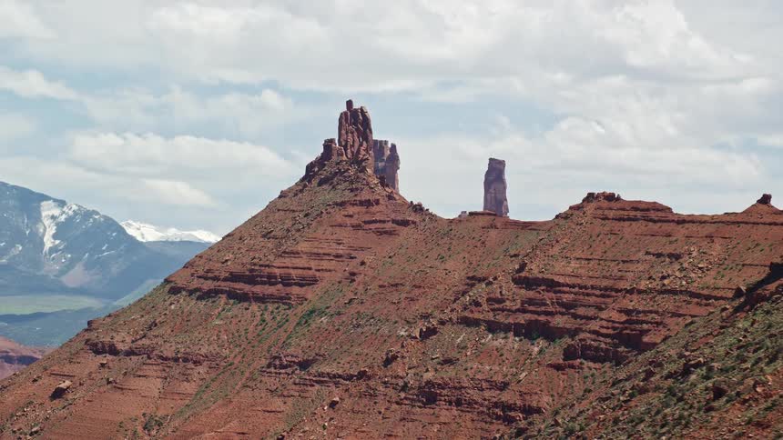  aerial footage reveals Castleton Tower in sunny Moab Utah as the camera flies by two buttes capturing the arid and beautiful desert landscape of the Southwest United States during a daytime shoot