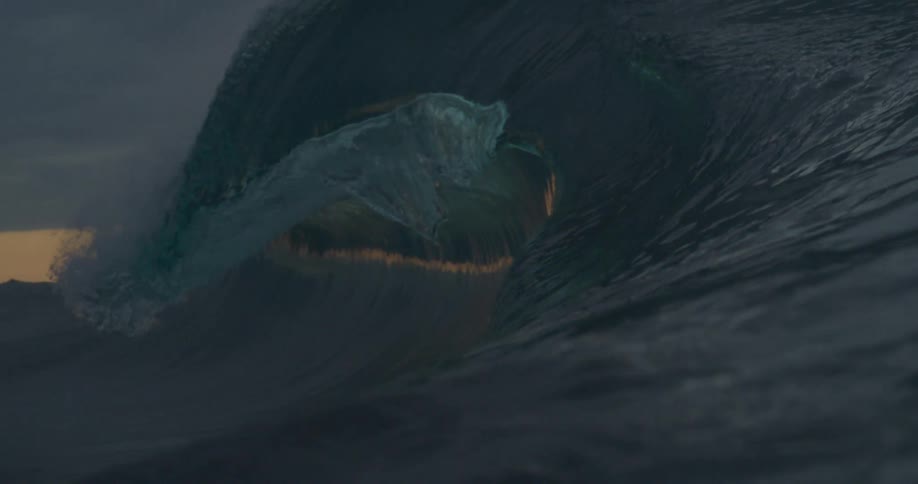 Waves crest and break in the ocean at dusk