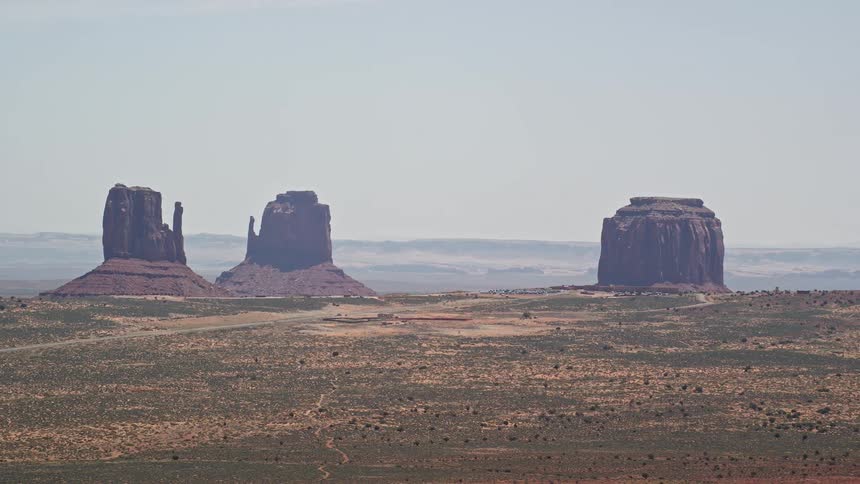 Aerial footage of majestic tall formations and a hazy desert valley in Monument Valley Utah Arizona
