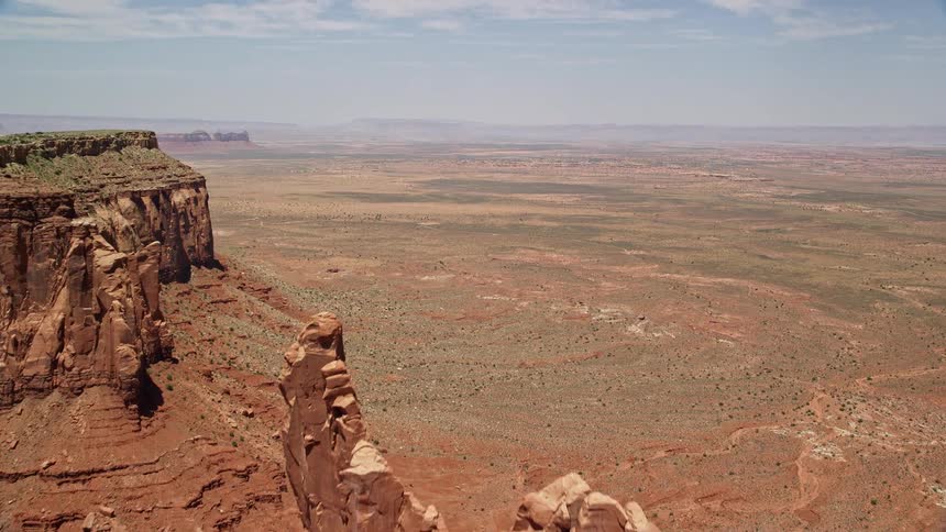 Approaching and flying over Setting Hen Butte in Monument Valley Utah and Arizona capturing the natural beauty of the arid desert landscape with haze and sunshine