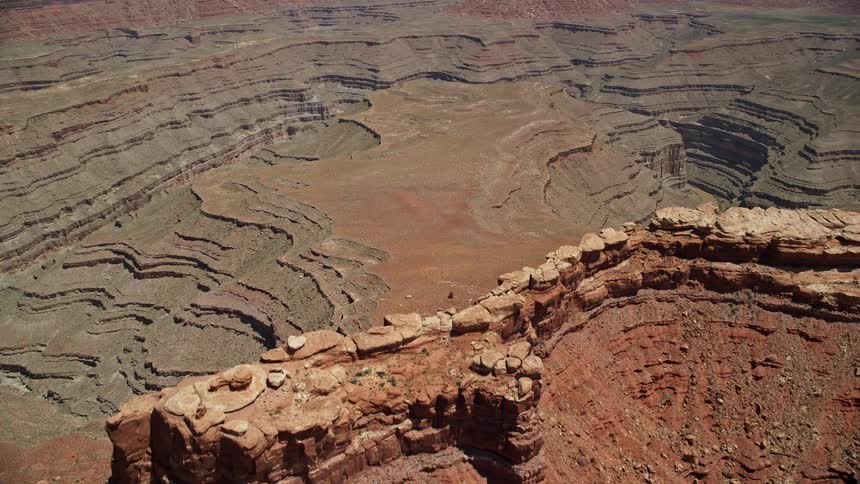 Aerial footage flying over a butte near deep desert canyons in the Navajo Nation Reservation showcasing the arid landscape and red mountains of the Southwest United States