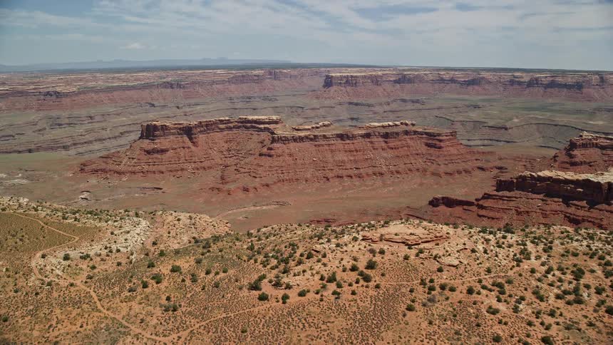 Aerial footage of flying over a canyon approaching a butte in the Navajo Nation Reservation showcasing the stunning desert landscape of Utah and Arizona