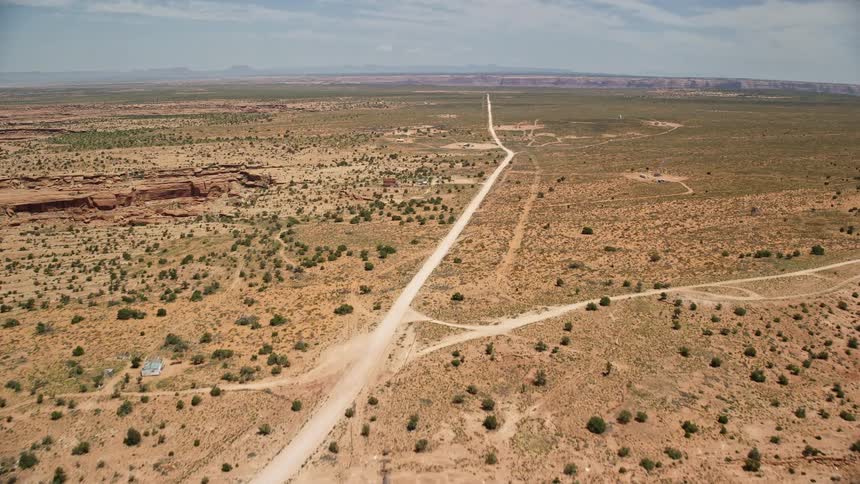 Approaching rustic rural homes alongside Douglas Mesa Road on the Navajo Nation Reservation with breathtaking views of the desert landscape and tribal lands of Utah and Arizona