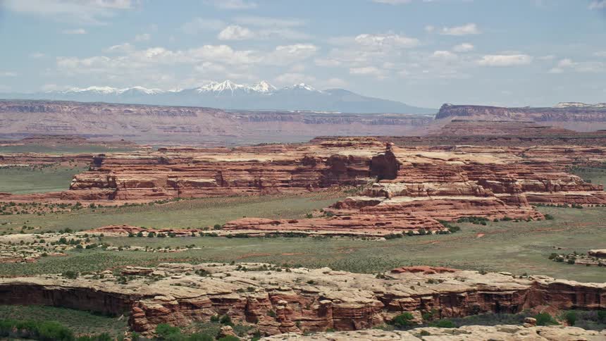 an aerial view of the stunning rock formations in Canyonlands National Park Utah showcasing the arid desert landscape and snow-capped mountains in the backdrop