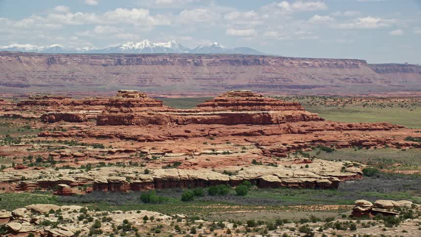 an aerial view of a desert butte in Canyonlands National Park Utah showcasing the stunning Southwest landscape with red mountains and bushes against a hazy backdrop