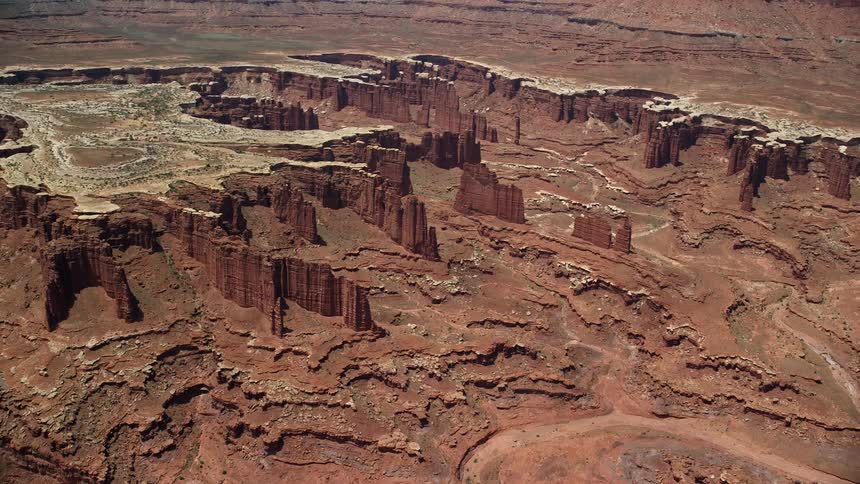  aerial footage capturing the breathtaking view of flying away from steep buttes Monument Canyon and White Rim in Canyonlands National Park Utah showcasing the arid landscape and famous landmarks
