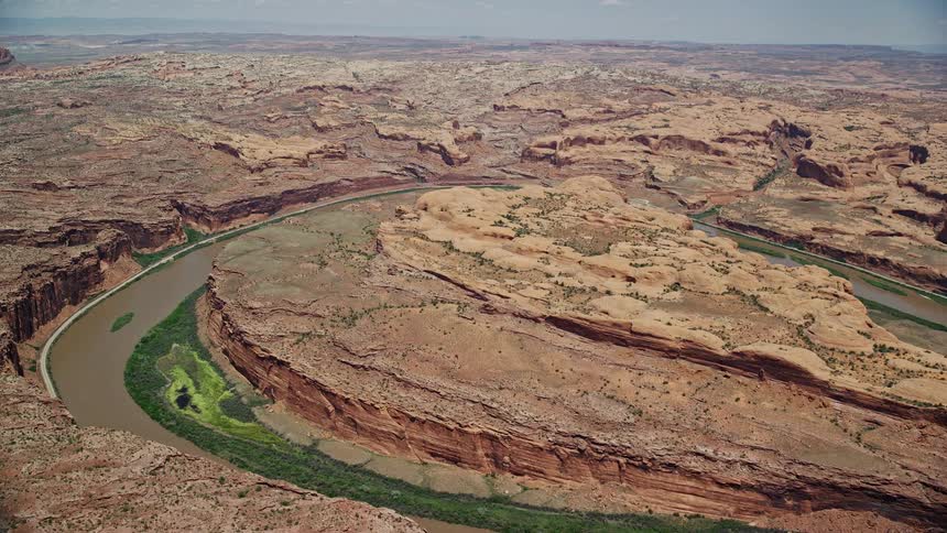 aerial footage capturing the breathtaking loop of the Colorado River and stunning rock formations as we fly towards them in Moab Utah showcasing the natural beauty of an arid sunny and wild canyon landscape