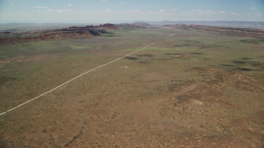 Aerial footage of flying over Arches Scenic Drive in a desert valley showcasing the stunning landscape of Arches National Park in Utah during summertime