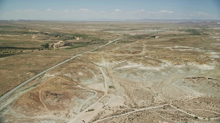 Approaching Highway 191 in Moab Utah an aerial view captures the desert valley landscape and a highway with cars passing by under sunny skies