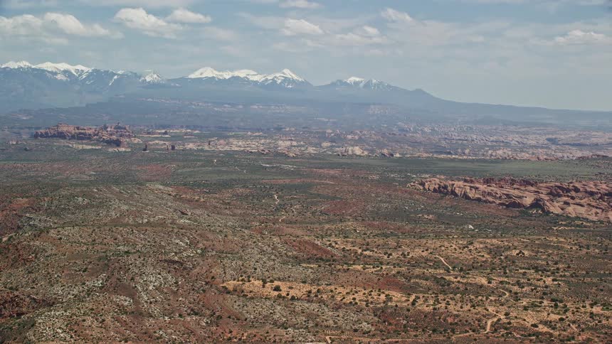 an aerial view of the iconic rock formations and snow-capped mountains in Arches National Park Utah showcasing the stunning natural beauty of the southwest landscape during a sunny summer day