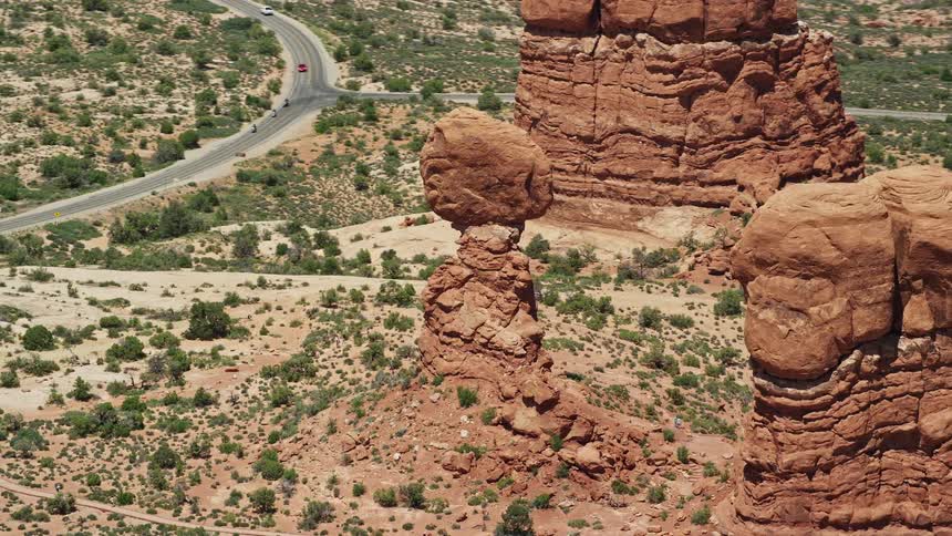  aerial footage of Balanced Rock rock formation at Arches National Park Utah showcasing the arid desert landscape and famous landmark during a sunny day in the Southwest United States