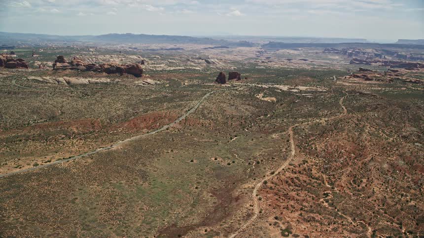 Aerial footage flying over Ham Rock and Balanced Rock near Arches Scenic Drive showcasing the stunning rock formations and scenic landscapes of Arches National Park in Utah during summer