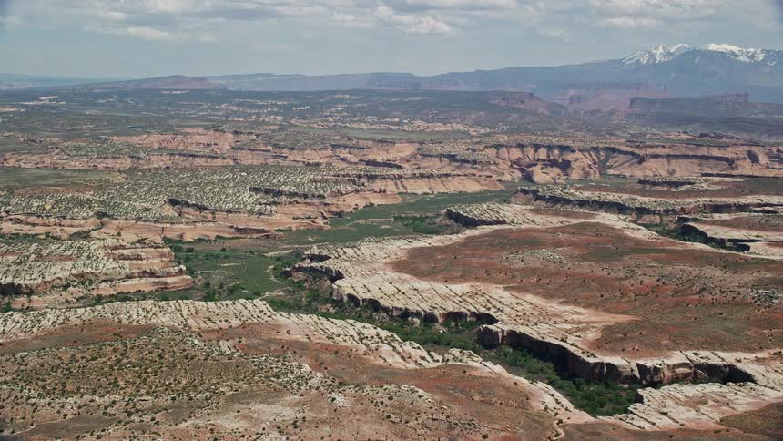 Approaching the Salt Wash Canyons at Arches National Park in Utah this aerial footage captures the breathtaking desert landscape with green shrubs and rocky cliffs