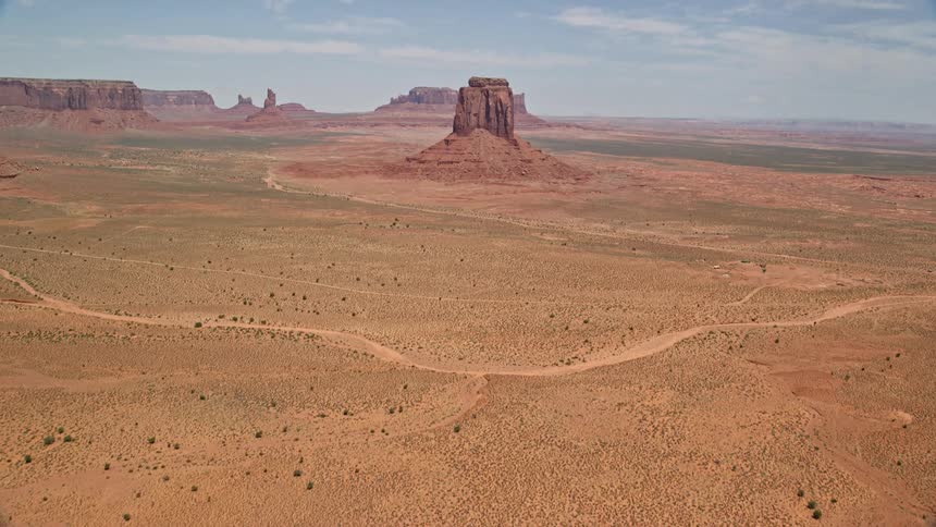  aerial footage reveals East Mitten Butte as the camera tilts up from a desert valley in Monument Valley Utah and Arizona showcasing the natural beauty of the arid landscape
