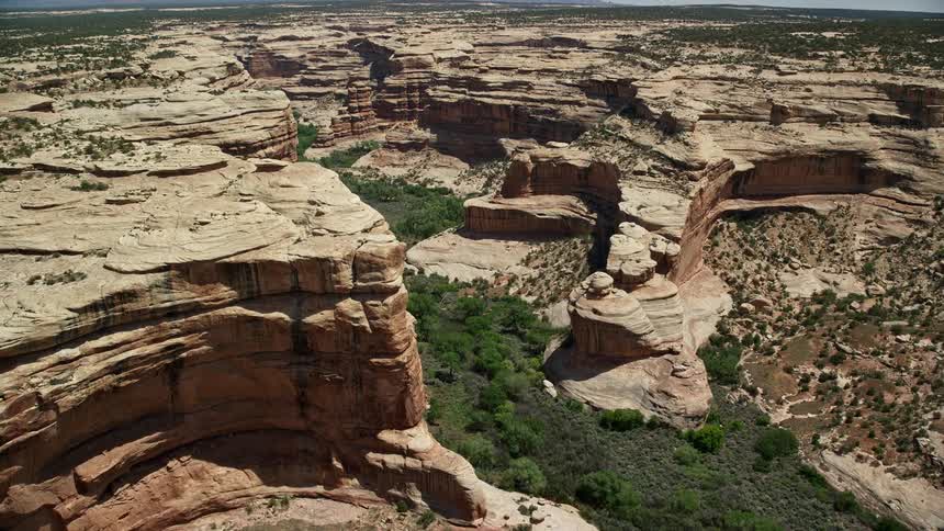 Approaching Grand Gulch in Utah thisaerial footage captures a panoramic view of the deep canyon on a sunny day showcasing the arid beauty of the Southwest United States