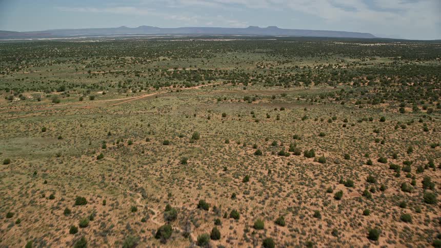 Aerial footage of a desert landscape over Slick Horn Road and desert valley showcasing the arid terrain and transportation routes in cedar mesa Utah