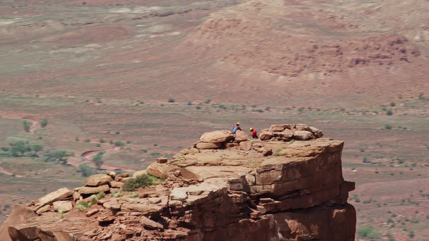  aerial footage captures an orbit around two rock climbers at the summit of Castleton Tower in Moab Utah during a sunny day in the desert