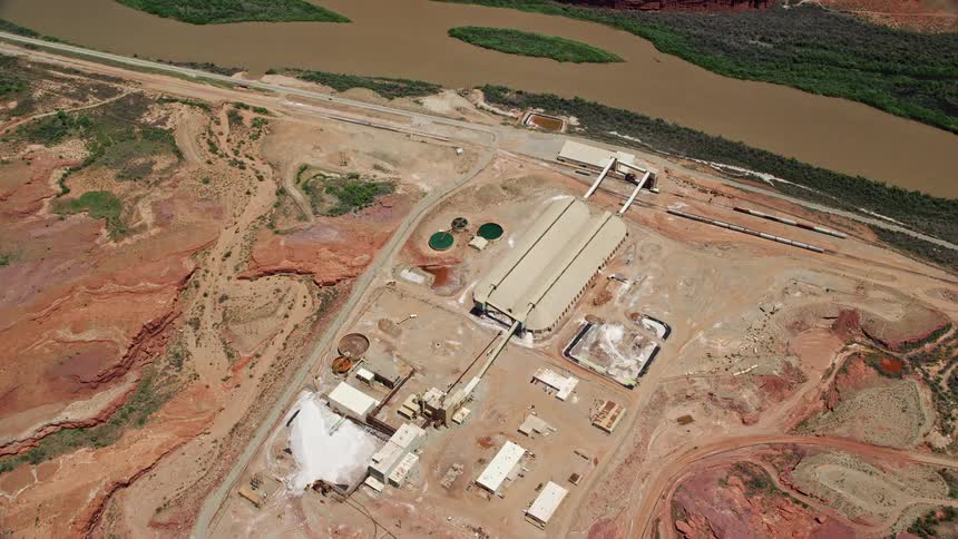  aerial footage showcasing an industrial manufacturing plant nestled in Utah's arid badlands with a bird's eye view of the Intrepid Potash facility by the Colorado River in Moab