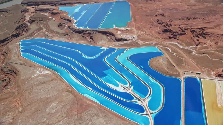 Aerial footage of potash ponds in an arid desert valley in Moab Utah as the camera flies away