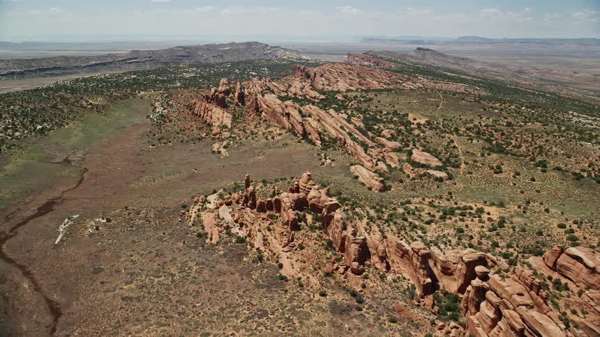 In this aerial footage fly over the stunning rock fins and desert plants of Eagle Park in Arches National Park Utah showcasing the breathtaking desert landscape and famous rock formations in the Southwest United States during a sunny summer day
