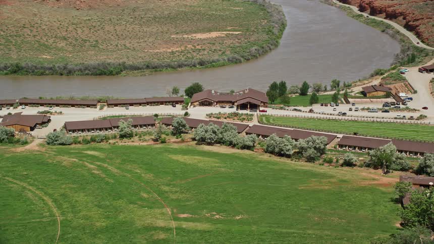  aerial footage showcasing the stunning Red Cliffs Lodge hotel located on the banks of the Colorado River in Moab Utah surrounded by arid desert landscapes and offering leisure activities and sightseeing opportunities in the sunny Southwest United States 