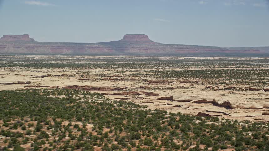  aerial footage capturing the breathtaking view of distant mesas across the arid and sunny desert landscape of Cedar Mesa Utah in the Southwest United States