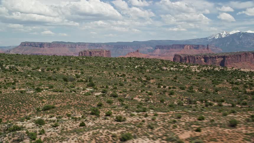 an aerial view of the mesmerizing Utah desert landscape with majestic mesas and buttes bathed in sunshine as seen from the top of Dry Mesa in Moab