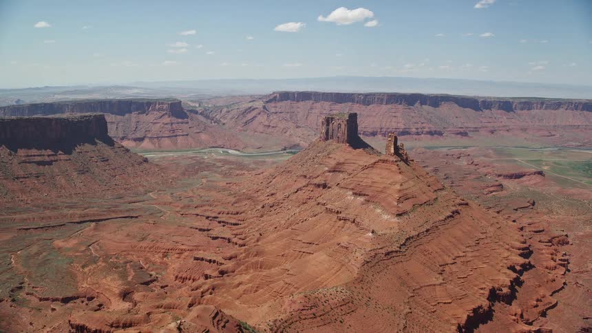 Approaching red buttes in the desert landscape of Moab Utah during a sunny summer day aerial shot