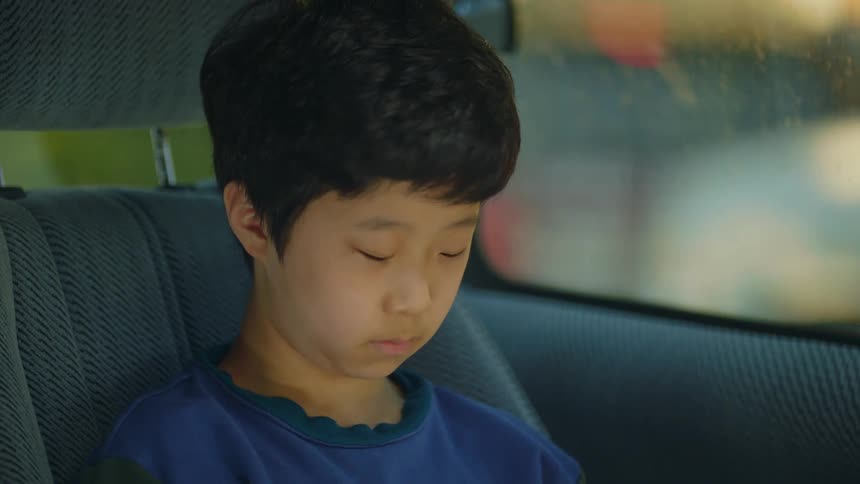 Asian boy sitting in the back seat of a car