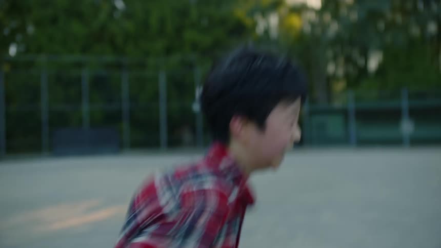 Boy smiles while running across sports field on a sunny day