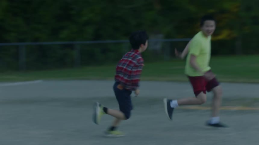 Boy with plaid shirt and shorts plays with schoolmates running and having fun