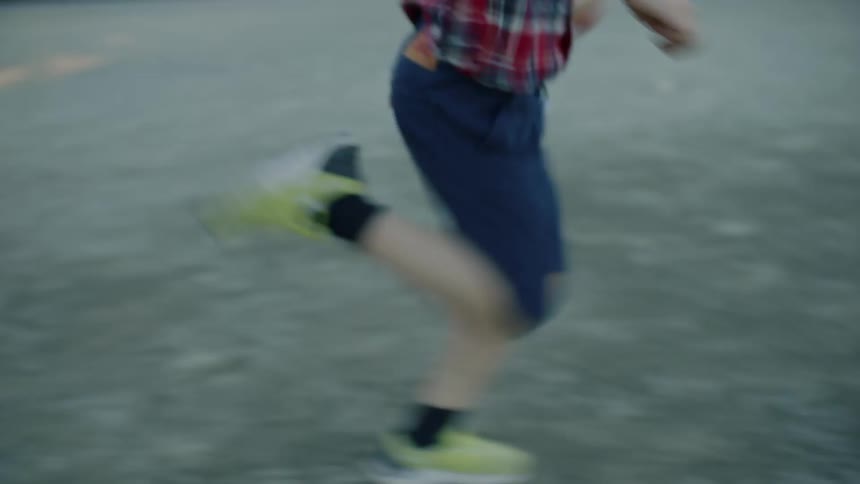 Student with plaid shirt and shorts running and laughing