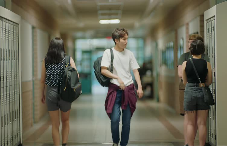Student walking down hallway exchanges greetings with other students