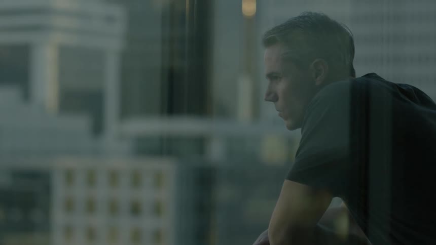 A man looks at a view of the city out of his window