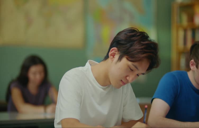 Asian student sits at desk and writes