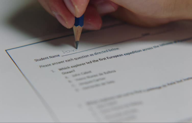 Close up of hand writing down his name on exam paper