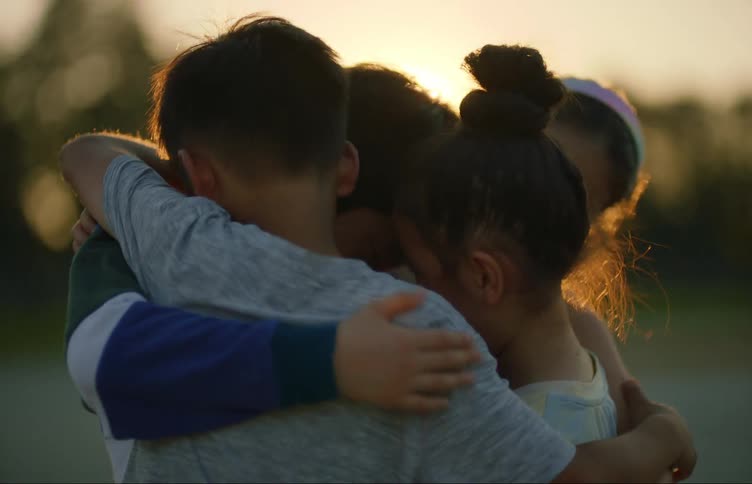 A group of children playing and cuddling each other at sunset