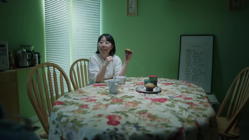 Mother sits at the dining table while the son walked past moody