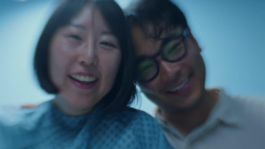Mother wearing hospital gown and husband smile down at child