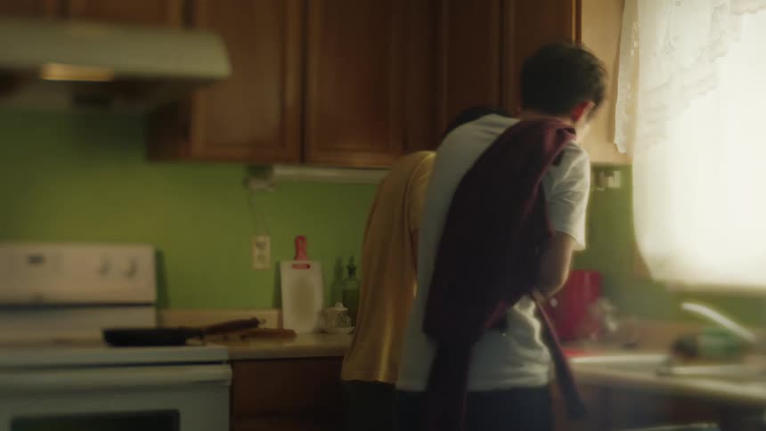 Father chopping vegetables in the kitchen and his son grabbing a small piece and eating it