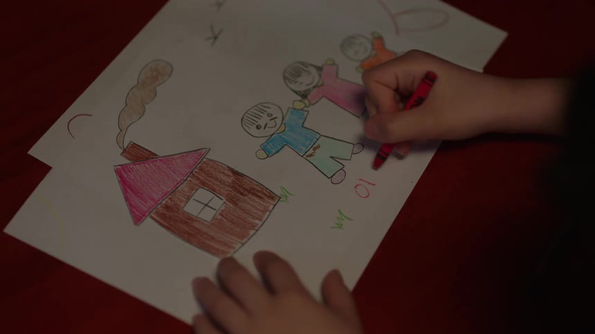 Hands holding crayon complete drawing on paper