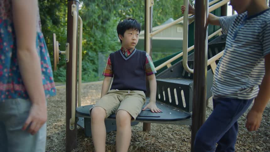 Two white children run up to confront asian boy on playground
