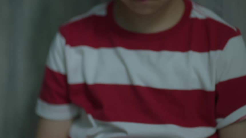 A young boy looks sadly down at a broken plate on the floor in front of him