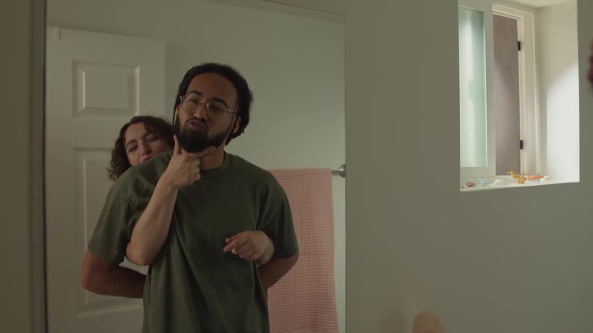 A man and a woman playing in front of a mirror inside the bathroom