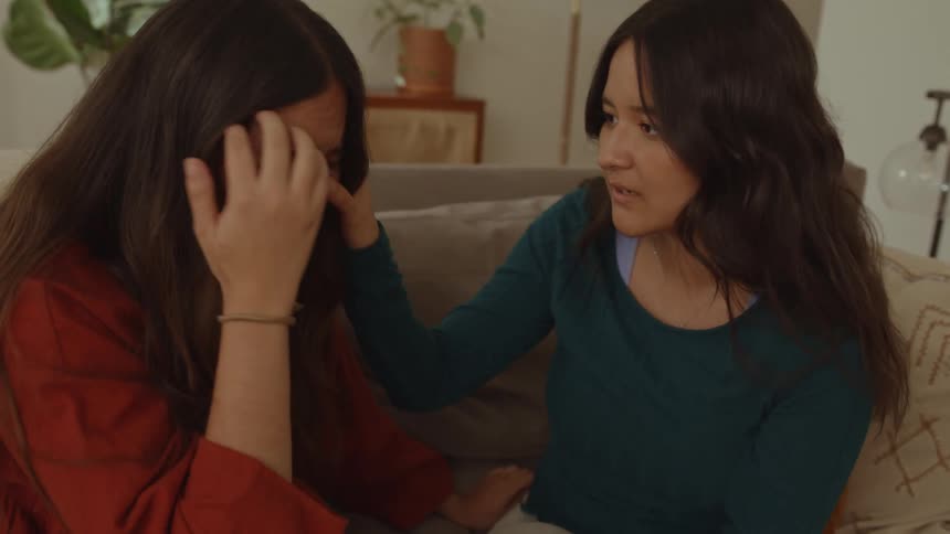 Woman consoles and listens to a friend crying in the couch at home