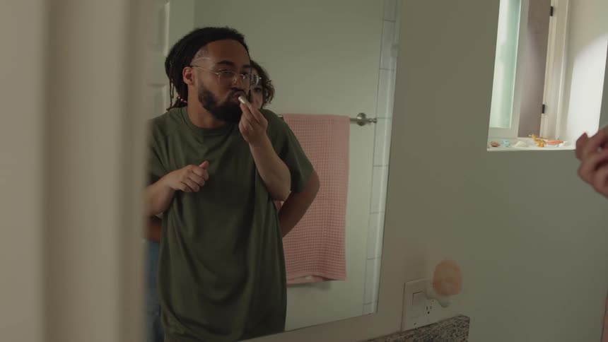 Girlfriend puts lipstick on her boyfriend mouth in front of a mirror