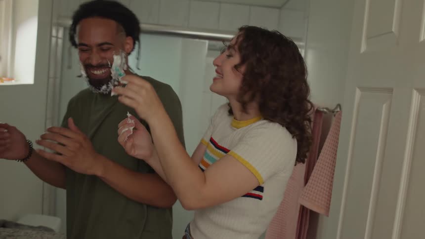 Girlfriend and boyfriend play with shaving foam and razor in the bathroom